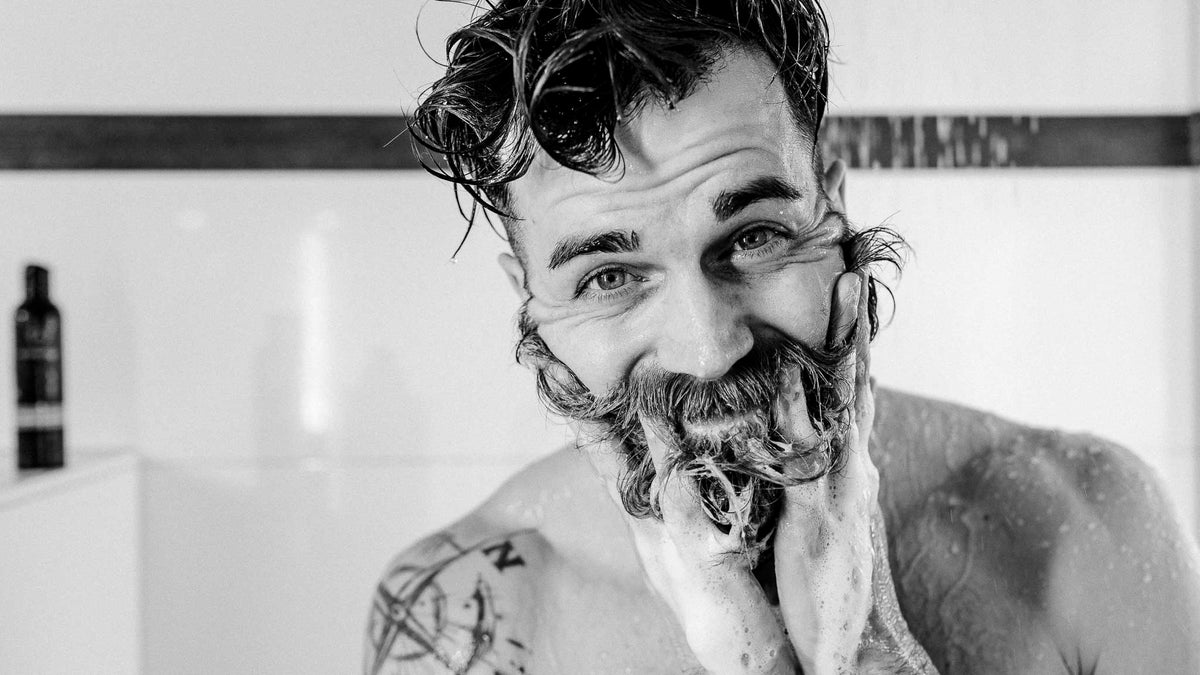 Mann zwirbelt nassen Schnurrbart in der Dusche