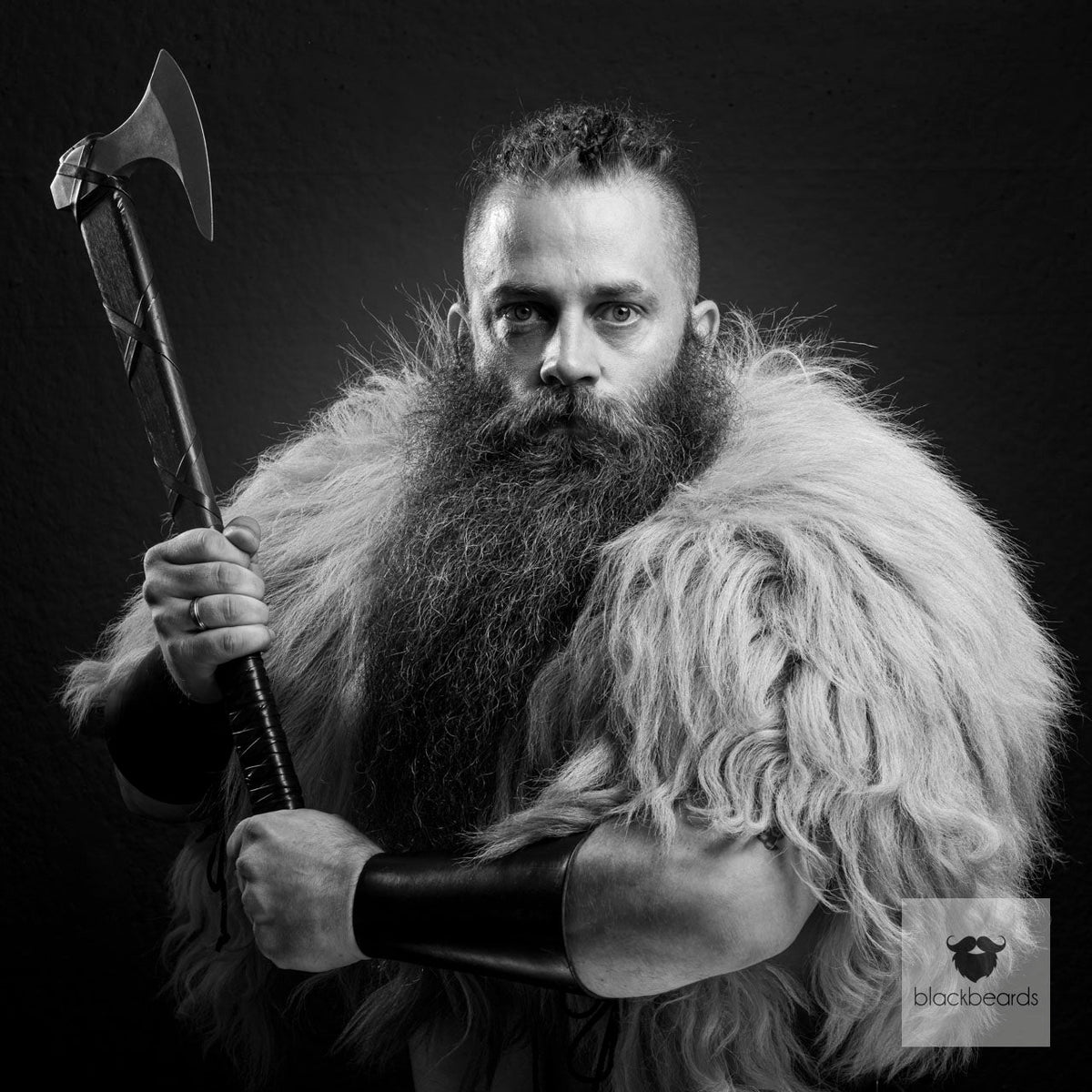 Mann mit Axt, Fellumhang und langem Vollbart im Wikinger-Look