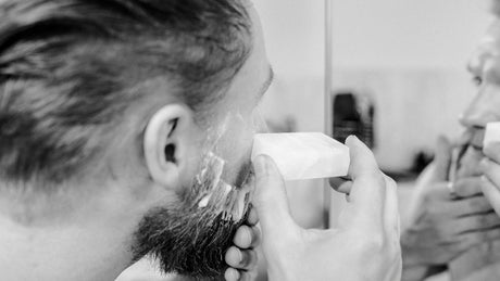 Mann reibt Wange mit Alaunstein nach Rasur
