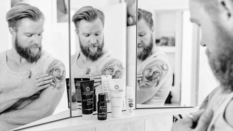 Mann cremt Schulter Tattoo ein vor Spiegel