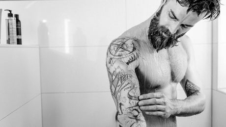Mann seift Tattoo Arm unter der Dusche ein