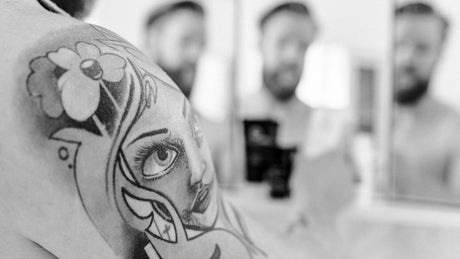 Tattoo auf Schulter Nahaufnahme Mann im Hintergrund