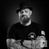 Bartträger mit Hut, gestutztem Vollbart und tätowierten Armen, Schwarz-Weiß-Porträt für Blackbeards